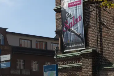Kulturhaus Babelsberg mit Salsa-Banner, Wegweisern und Stadtplan-Stele