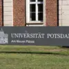 Schild „Universität Potsdam – Am Neuen Palais“ vor einem Backsteingebäude