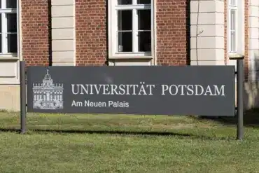 Schild „Universität Potsdam – Am Neuen Palais“ vor einem Backsteingebäude