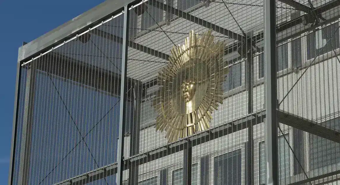 Goldene Sonne in einer Gitterkonstruktion vor blauem Himmel