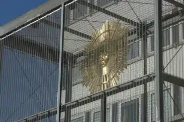Goldene Sonne in einer Gitterkonstruktion vor blauem Himmel