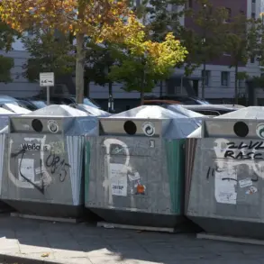 Mit Graffiti besprühte Altglascontainer am Straßenrand vor Wohnhäusern
