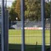 Blick durch einen Gitterzaun auf Rasen und Tribüne des Karl-Liebknecht-Stadions