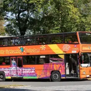 Orangefarbener Doppeldecker-Bus für Stadtrundfahrten in einer Allee