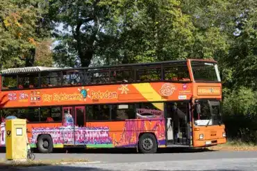 Orangefarbener Doppeldecker-Bus für Stadtrundfahrten in einer Allee