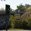 Fußgängerampel vor einer Bahnunterführung mit gelbem Wegweiser