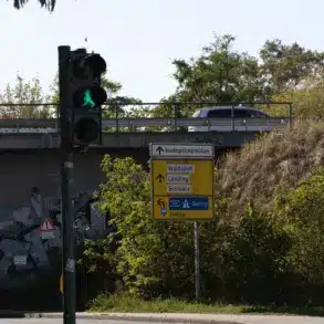 Fußgängerampel vor einer Bahnunterführung mit gelbem Wegweiser