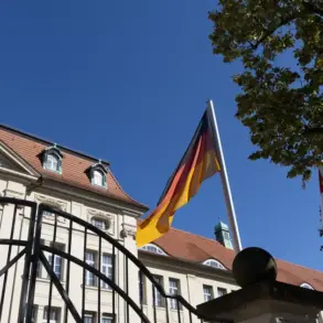 Deutschland- und Brandenburg-Flagge vor einem historischen Regierungsgebäude hinter einem Eisentor