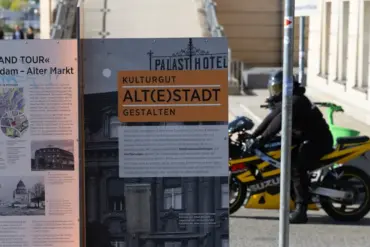 Infostele „Grand Tour Potsdam – Alter Markt“, dahinter ein Motorradfahrer
