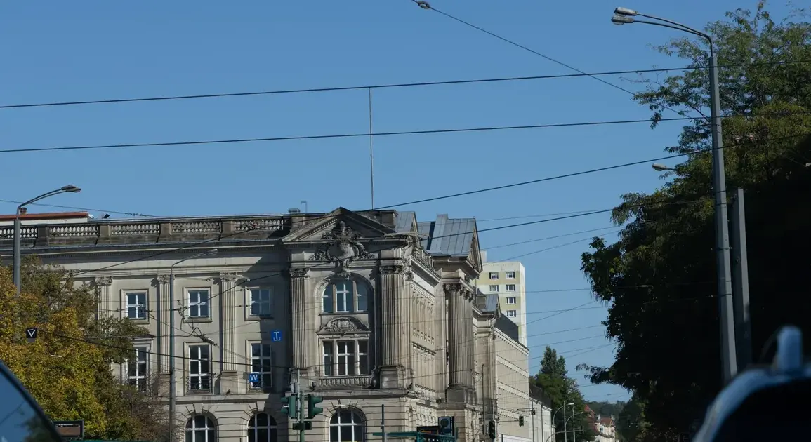 Historisches Verwaltungsgebäude an einer Kreuzung mit Straßenbahnoberleitungen