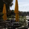 Leerer Biergarten mit Holztischen und geschlossenen gelben Sonnenschirmen