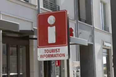 Rotes Schild „Tourist Information“ an einer Hauswand