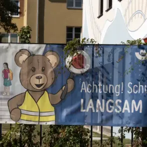 Banner der Unfallkasse Brandenburg „Achtung! Schulkinder! Langsam fahren“ an einem Zaun