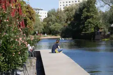 Frau sitzt am Ende eines Stegs an der Havel, daneben Café-Tische