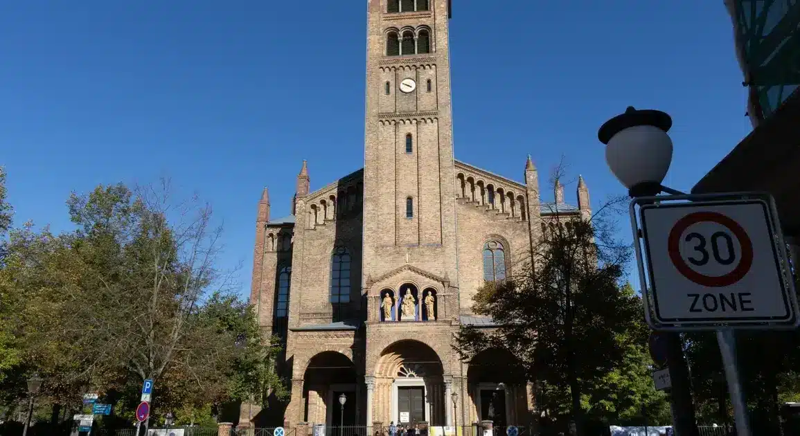 Katholische Kirche St. Peter und Paul mit Glockenturm, davor ein Tempo-30-Zonen-Schild