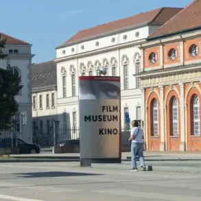 Stele „Filmmuseum Kino“ vor dem Marstall, daneben eine Haltestelle