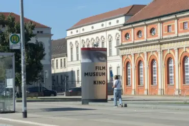 Stele „Filmmuseum Kino“ vor dem Marstall, daneben eine Haltestelle